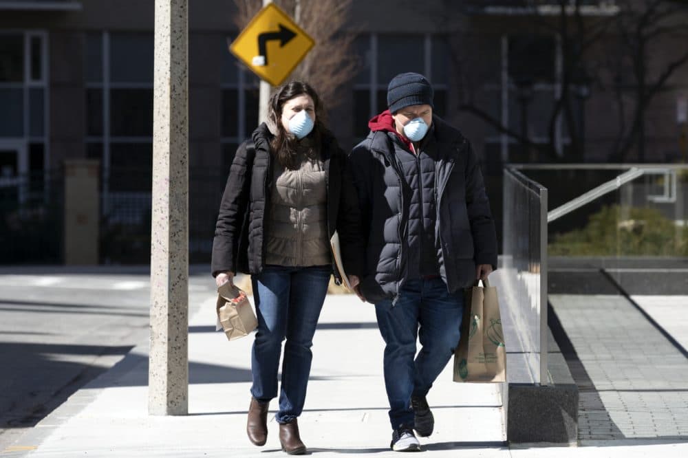 A couple wear masks while walking in Boston on Saturday. (Michael Dwyer/AP)
