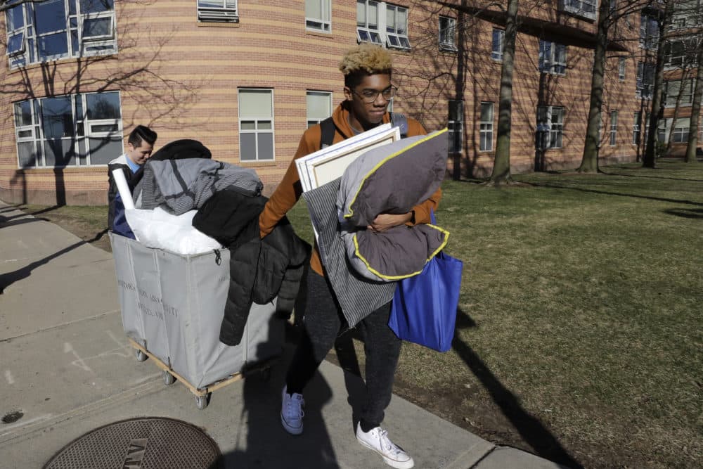 Northeastern University sophomore Philip Thomas, of Hamden, Conn., front, pulls a cart of belongings as he moves out of his residence hall as classmate Jarrett Anderson, of Las Vegas, left, assists him, Sunday, March 15, 2020, in Boston. Students have been asked by the school to move out of residence halls out of concern about the spread of the coronavirus. (Steven Senne/AP)