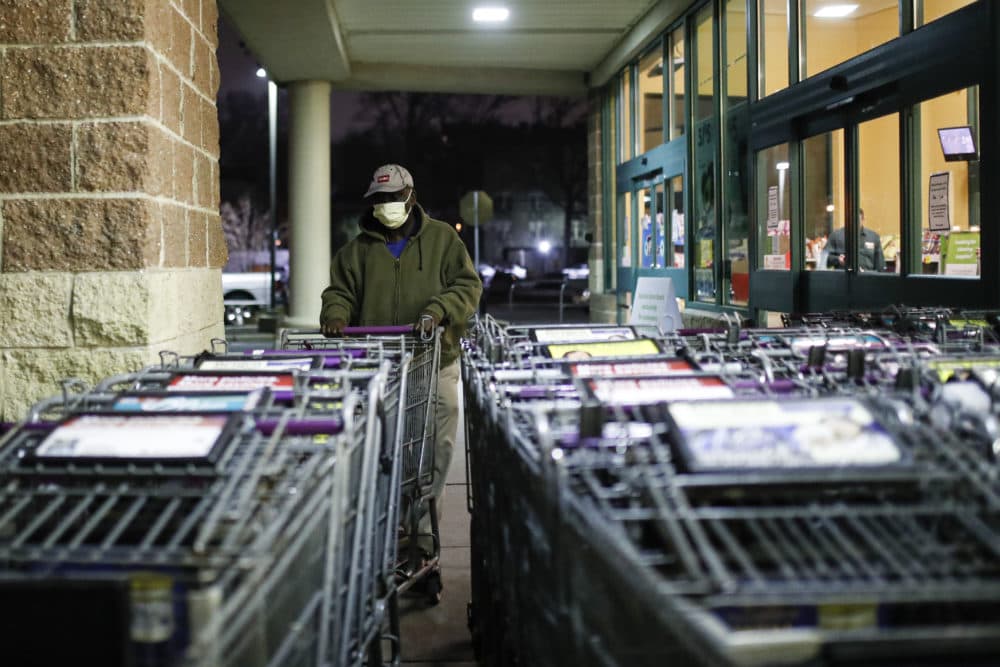 A customer wearing protective gloves and a face mask selects a cart outside a supermarket. (John Minchillo/AP)