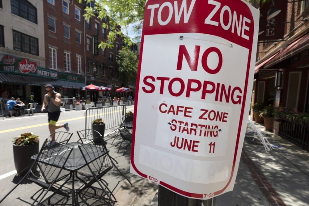 A man jogs past cafe tables placed in the closed parking lane on Hanover Street, Friday, June 12, 2020, in the North End neighborhood of Boston. (Michael Dwyer/AP)