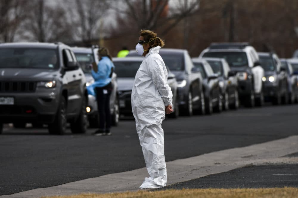 A healthcare worker watches over the line of people waiting to be tested for COVID-19 at the state's first drive-up testing center in Denver. (Michael Ciaglo/Getty Images)