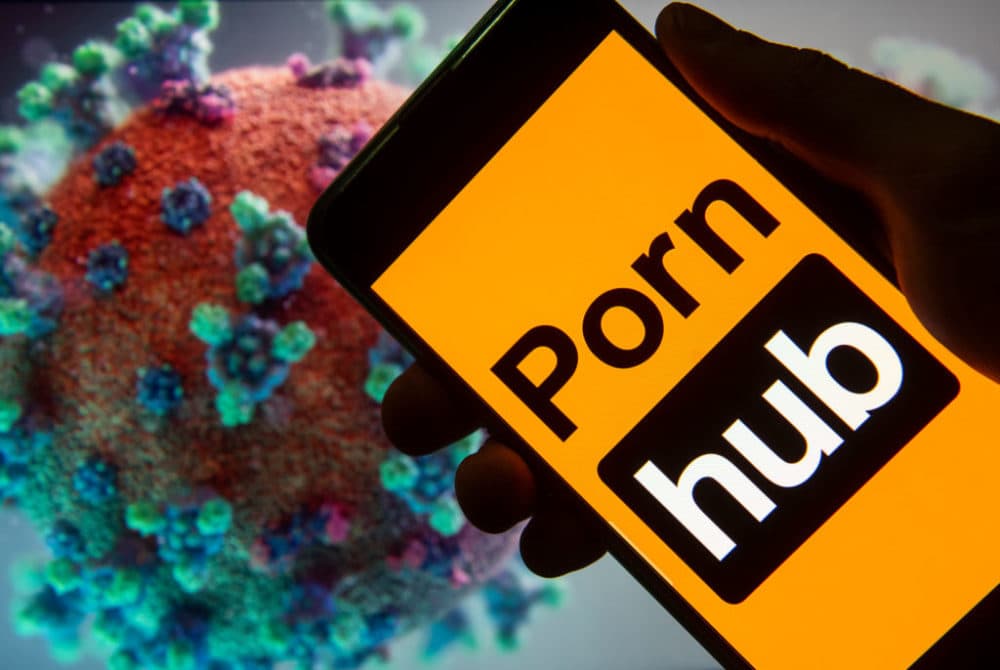 In this photo illustration the adult pornographic video sharing website Pornhub logo seen displayed on a smartphone with a computer model of the COVID-19 coronavirus on the background. (Photo Illustration by Budrul Chukrut/SOPA Images/LightRocket via Getty Images)