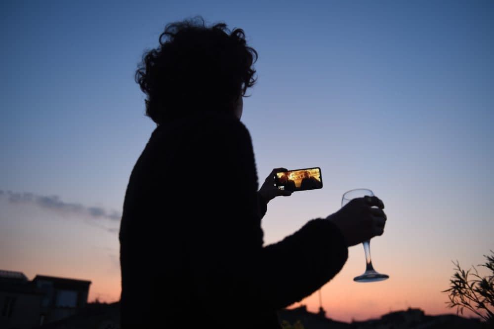 A woman drinks a glass of wine as she speaks and shares a drink with friends via a video call on March 26, 2020, in Bordeaux, southwestern France, in the evening on the tenth day of a lockdown aimed at curbing the spread of the COVID-19 (novel coronavirus) in France. (NICOLAS TUCAT/AFP via Getty Images)