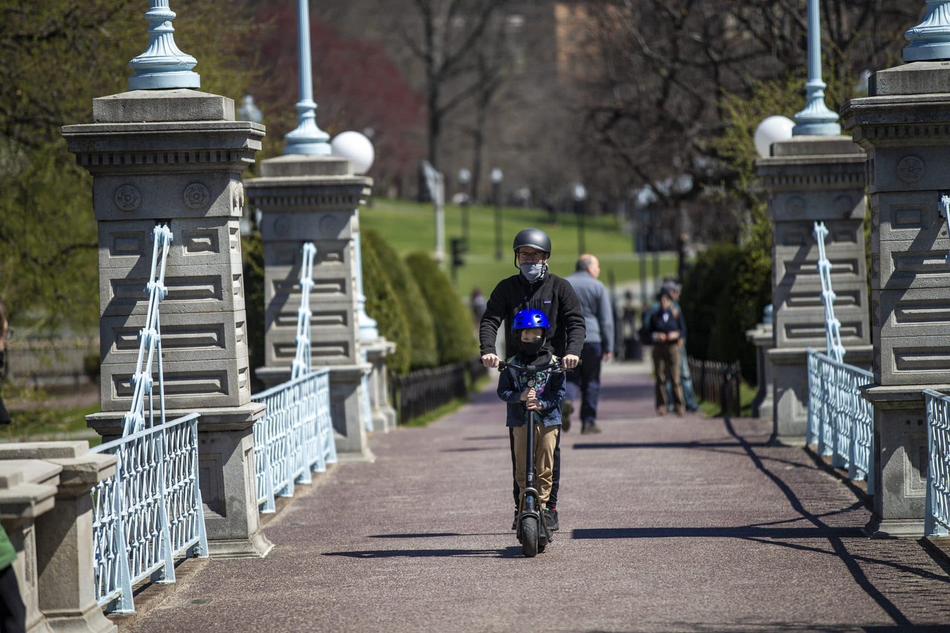 A man and his son ride an electric scooter over the Boston Public Garden Bridge. (Jesse Costa/WBUR)
