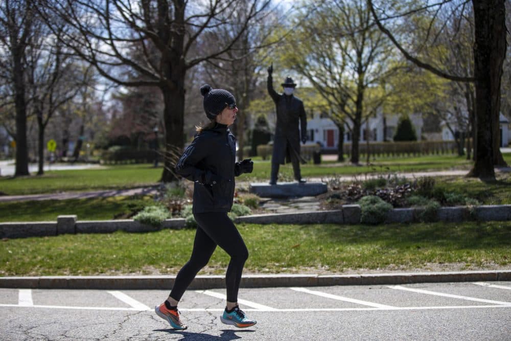 As she performs a virtual half-marathon to keep up her training for September, Hopkinton resident Joy Donohue runs past “The Starter” statue in the town's common -- the site of the start of the Boston Marathon. (Jesse Costa/WBUR)