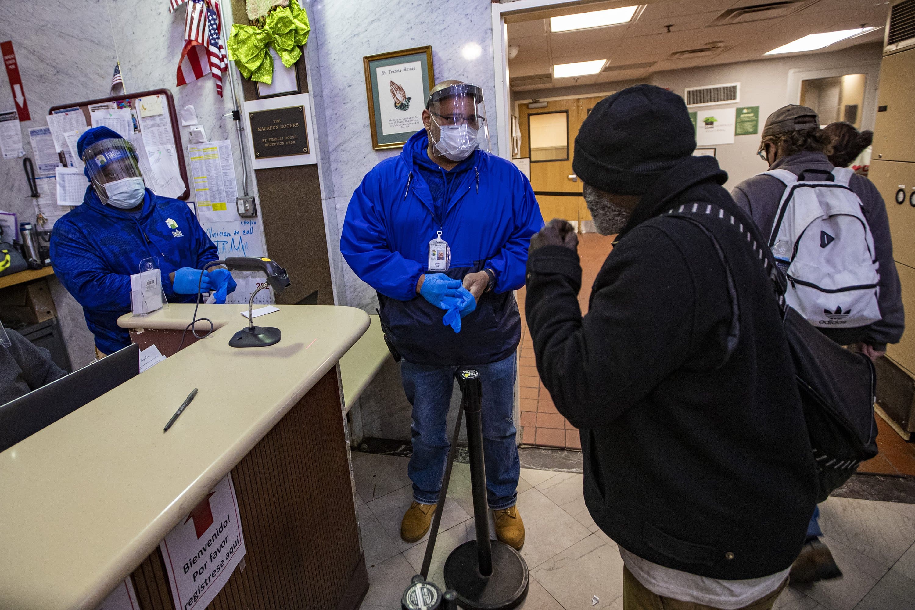 Angel Marte puts on a pair of nitrile gloves before working on some paperwork for a guest entering St. Francis House in Boston. (Jesse Costa/WBUR)