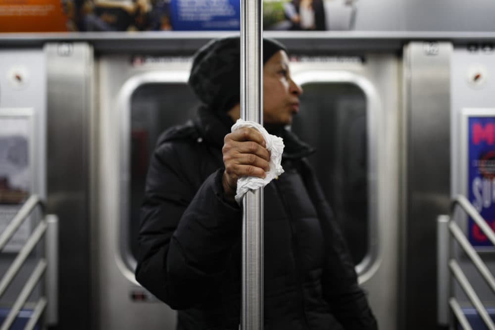 A subway customer uses a tissue to protect her hand while holding onto a pole as COVID-19 concerns drive down ridership, Thursday, March 19, 2020, in New York. (John Minchillo/AP Photo)