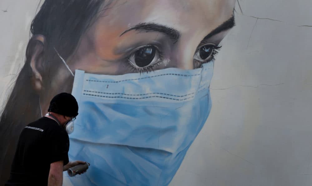 Graffiti artist Bram De Ceurt works on a painting of a nurse with a mask to protect against coronavirus in Antwerp, Belgium, Thursday, March 26, 2020. (Virginia Mayo/AP)