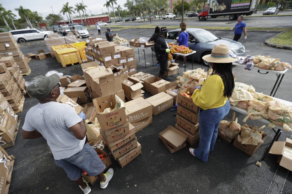Workers hand out bags of food during a food distribution event, Wednesday, April 1, 2020, in the Liberty City neighborhood of Miami. (Wilfredo Lee/AP Photo)