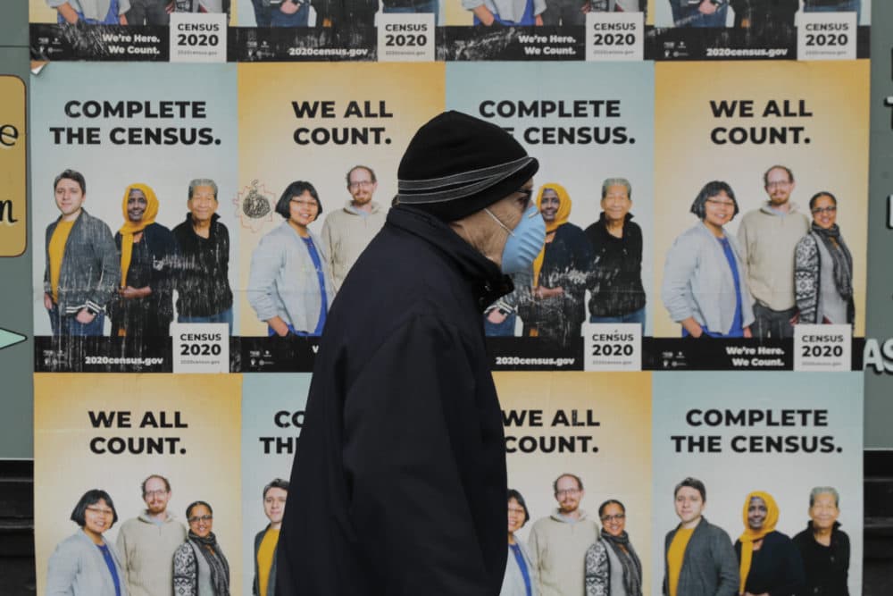 A man wearing a mask walks past posters encouraging participation in the 2020 Census, Wednesday, April 1, 2020, in Seattle's Capitol Hill neighborhood. (Ted S. Warren/AP)