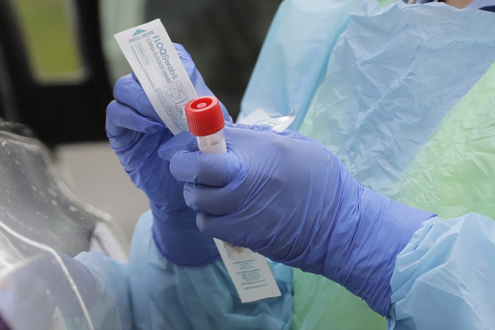 A nurse holds a vial and a swab at a drive-up coronavirus testing station at a hospital in Seattle. (Ted S. Warren/AP)