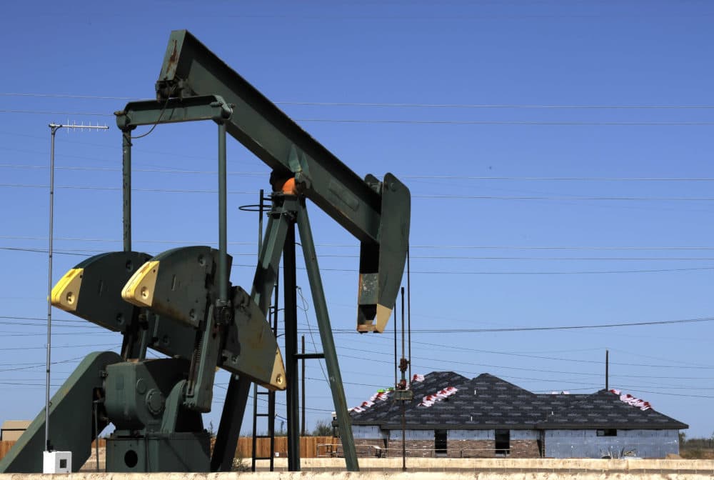 A pump jack works beside the site of new home construction in Midland, Texas. (Pat Sullivan/AP)