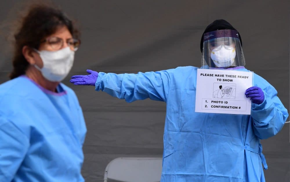 Medical personnel wear facemasks and display instructions for people arriving in their vehicles for COVID-19 testing on April 8, 2020, on the first day of testing at the Charles R. Drew University of Medicine in south Los Angeles.(FREDERIC J. BROWN/AFP via Getty Images)