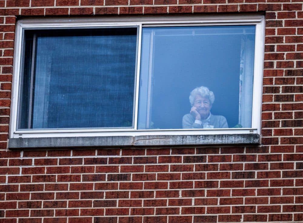 A resident of the Goodwin House senior living community, looks on as she listens to the DC area motown band &quot;The Tribe&quot; play a social distance concert in their parking lot in Arlington, Virginia, during the coronavirus pandemic on April 14, 2020. (ANDREW CABALLERO-REYNOLDS/AFP via Getty Images)