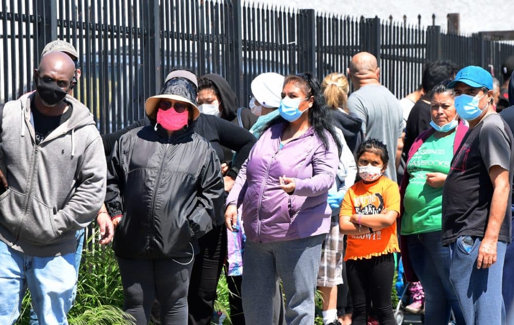 People wear their face masks as they wait in an emergency food distribution line outside the 88th Street Temple Church of God in Christ on April 14, 2020, in Los Angeles, California, during the coronavirus pandemic. (FREDERIC J. BROWN/AFP via Getty Images)