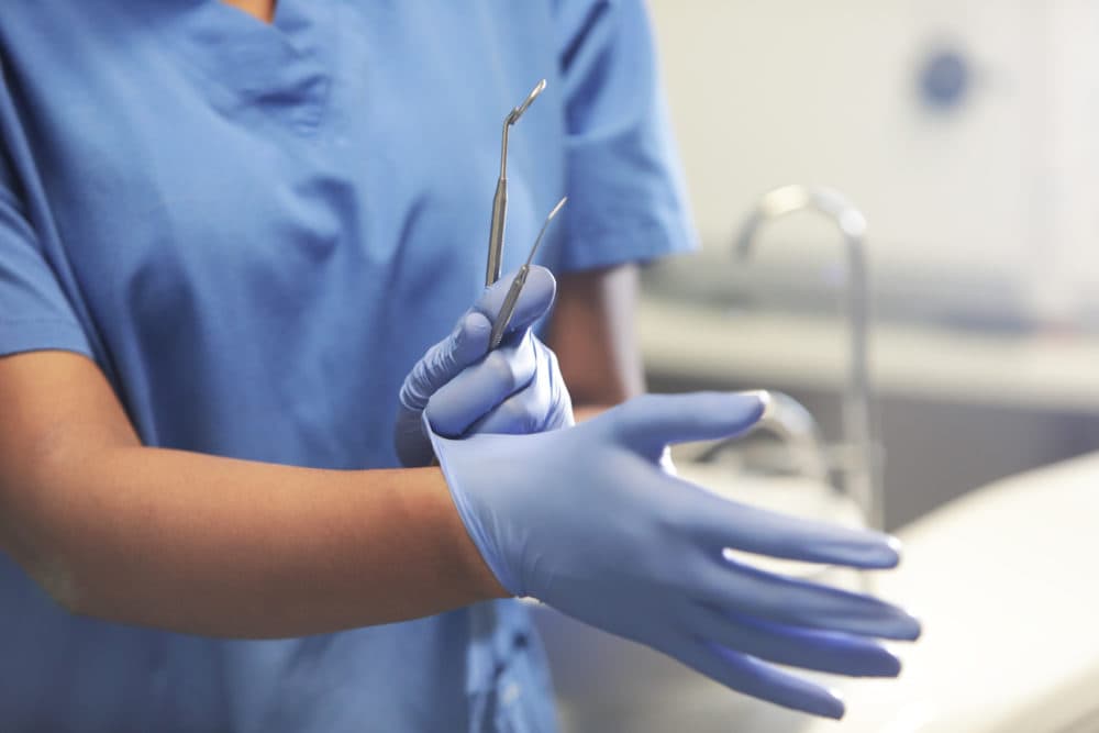 A dentist puts on protective gloves in this stock image. (Peter Cade/Getty)