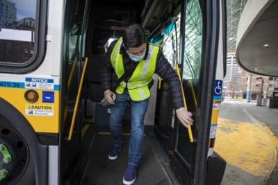 Diego Zabata disinfects an MBTA bus at Haymarket Station after it finished its route from Woodlawn in Everett. (Jesse Costa/WBUR)