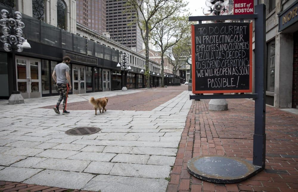 A man walks his dog through a deserted Faneuil Hall Marketplace on a Monday lunchtime during the coronavirus pandemic. (Robin Lubbock/WBUR)