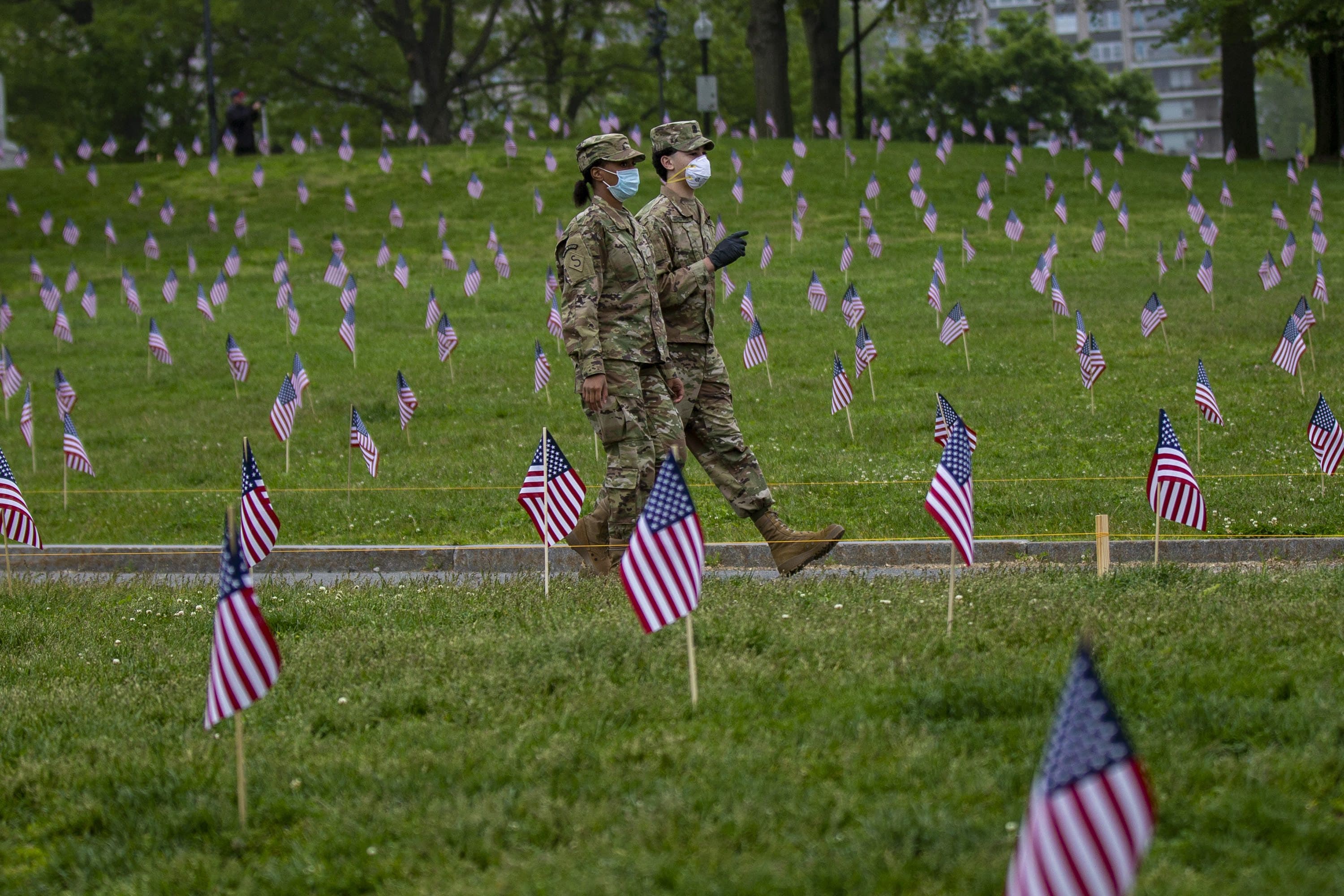 Lania Fitzparick and Goeorge Infante, members of the South Boston High School Junior ROTC, walk down a path through the flags planted at Boston Common honoring Mass. veterans who have died during war times. (Jesse Costa/WBUR)