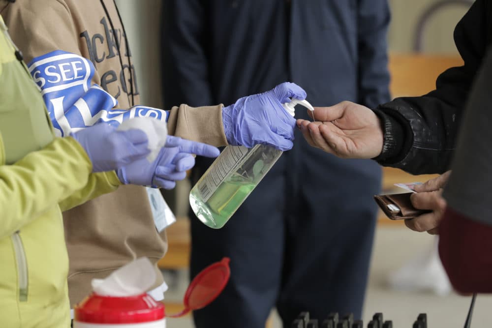In this March 27, 2020 photo, a patient picking up medication for opioid addiction is given hand sanitizer at a clinic in Olympia, Wash., The clinic is meeting patients outdoors and offering longer prescriptions to reduce risk of coronavirus infection. (Ted S. Warren/AP Photo)