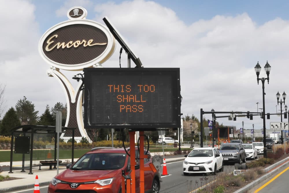 A roadway sign reads &quot;THIS TOO SHALL PASS&quot; as cars pass the entrance leading to the Encore Boston casino in Everett, Mass., April 22, 2020. (Charles Krupa/AP)