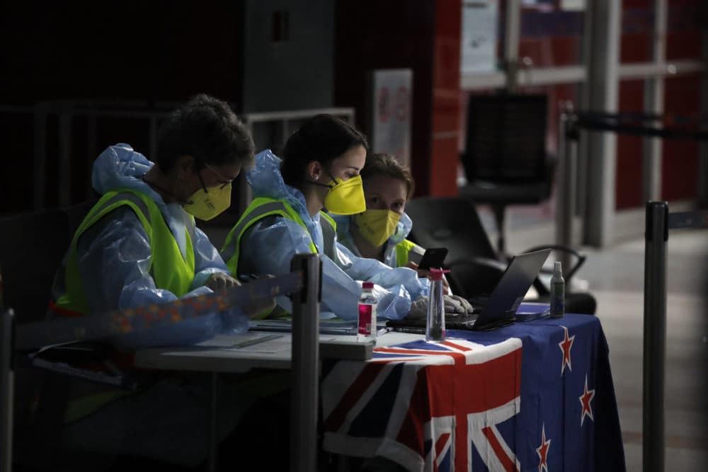 New Zealand officials go through the passengers list as stranded New Zealand nationals arrive to board a repatriation flight back home at the Indira Gandhi International airport in New Delhi, India, Thursday, April 23, 2020. New Zealand has closed the border to everyone except citizens and residents to stop the spread of new coronavirus. (Manish Swarup/AP)