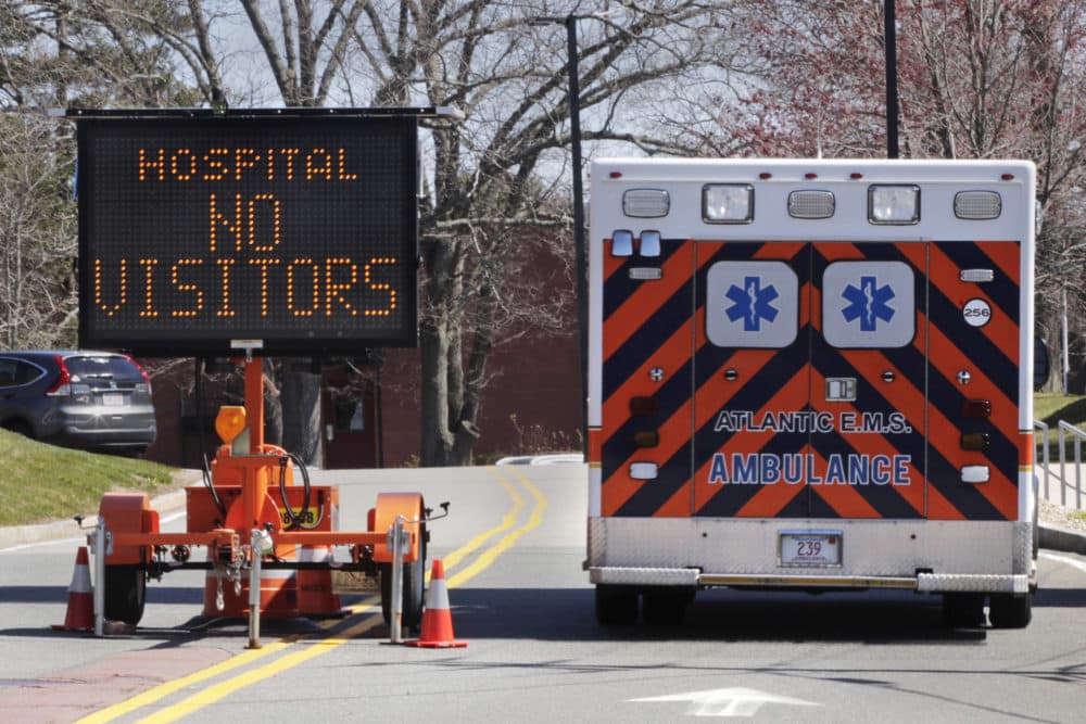 An ambulance rolls pass a sign alerting drivers, that due to the COVID-19 virus outbreak, no visitors are allowed at Essex County's Beverly Hospital in Beverly, Mass., Thursday, April 23, 2020. (Charles Krupa/AP)