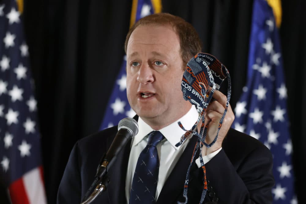 Colorado Gov. Jared Polis holds up a face mask to make a point during a news conference to update the state's efforts to stem the rise of the new coronavirus Monday, May 4, 2020, in the State Capitol in Denver. (David Zalubowski/AP)