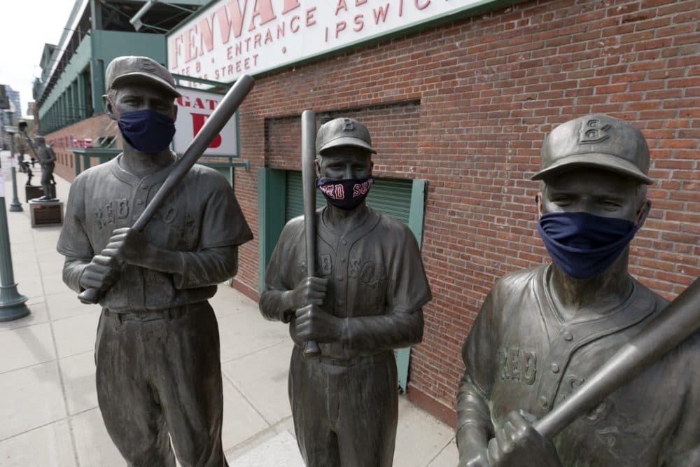 Statues of former Boston Red Sox greats, from left, Ted Williams, Bobby Doerr and Johnny Pesky, wear protective masks outside Fenway Park. (Michael Dwyer/AP)