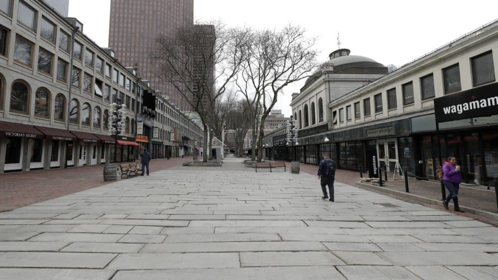 People walk through the nearly empty tourist area of Quincy Market, Wednesday, March 11, 2020, in Boston. (Steven Senne/AP)