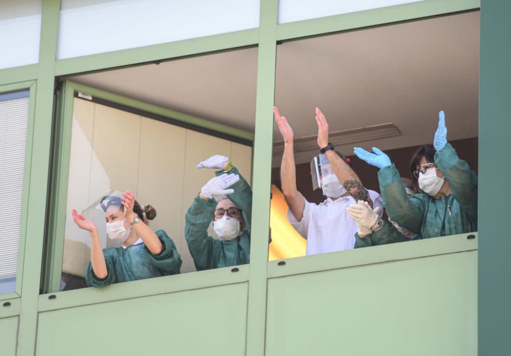Medical personnel cheers from the windows of a nursing home. (Piero Cruciatti/AFP/Getty Images)