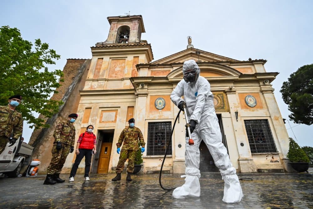 A member of the Italian Army, wearing protective overall and mask, sprays sanitizer outside of the Santuario della Madonna del Divino Amore church on May 13, 2020 in Rome during the country's lockdown. (Andreas Solaro/AFP/Getty Images)