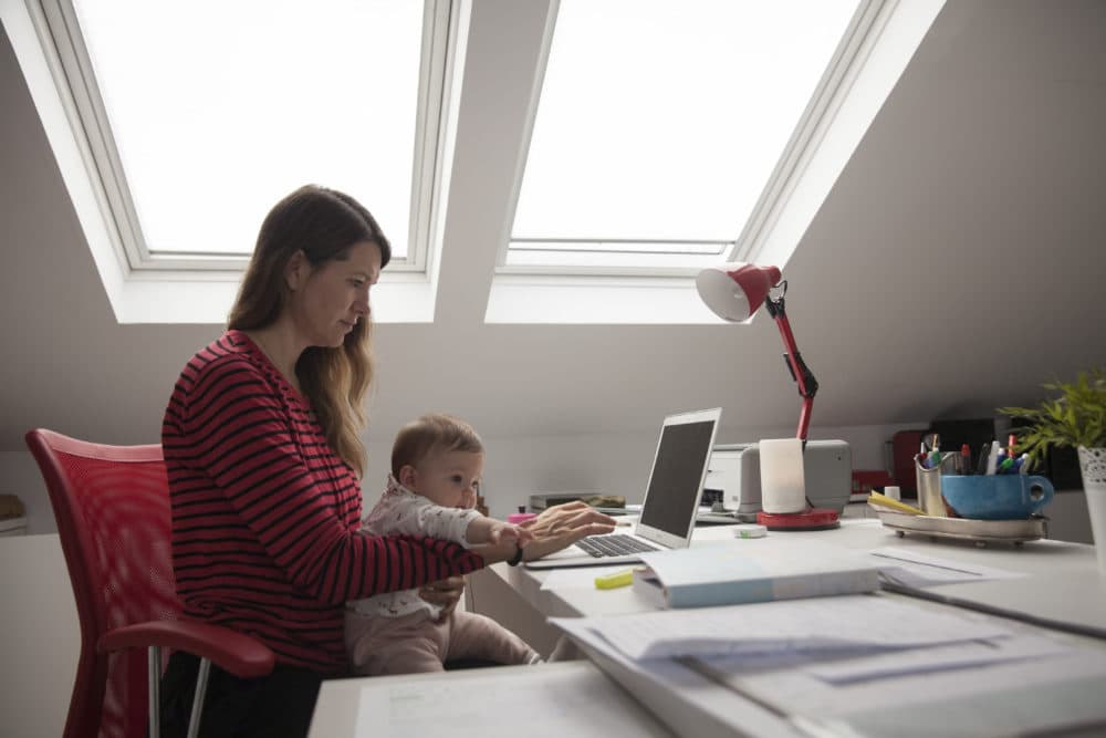 Virginia Bejar, the photographer's partner, strives to work at home while holding her 6-month-old daughter during the COVID-19 lockdown on May 11, 2020, in Majadahonda, Madrid, Spain. (Miguel Pereira/Getty Images)