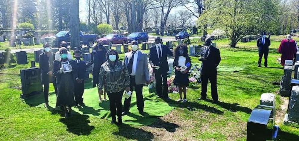 Relatives of Cynthia and Clasford Johnson, who were interred at Cedar Grove Cemetery last weekend, are shown by their grave. Only ten members of the family were allowed to be present at the burial. Photos courtesy Amos Monteiro