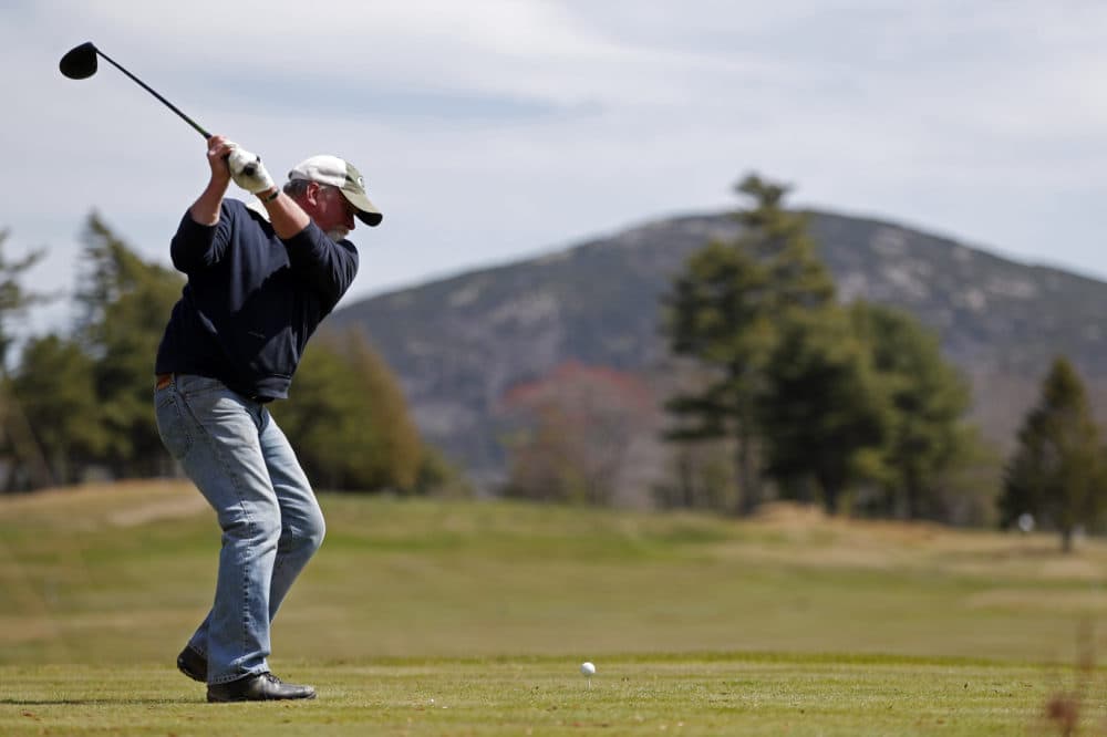 Not far from a mountain in Acadia National Park, background, Jack Gilley hits a tee shot at Kebo Valley Golf Club, Wednesday, May 6, 2020, in Bar Harbor, Maine. Some businesses in the state such as golf courses are reopening to state residents who live in the same county. The roads and facilities of Acadia National Park, however, remain closed.(AP Photo/Robert F. Bukaty)