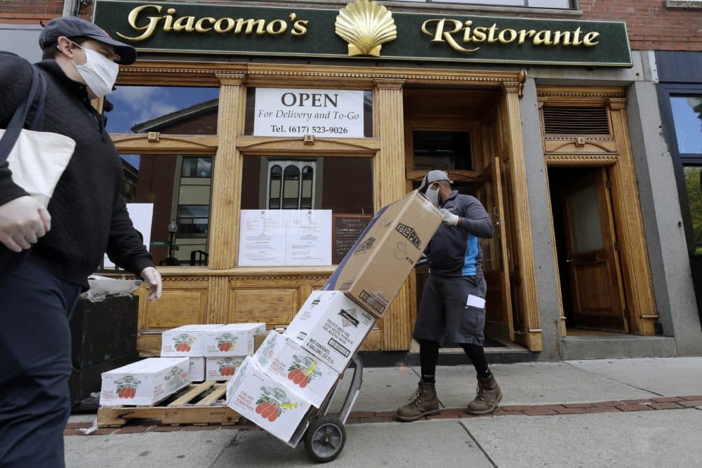A pedestrian wearing a protective mask passes a food delivery being made to a restaurant providing takeout service during the coronavirus pandemic on May 12 in the North End neighborhood of Boston. (Steven Senne/AP)