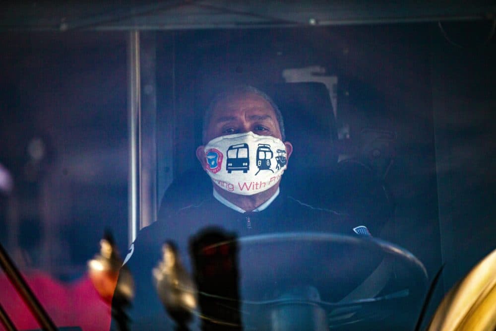 An MBTA bus driver stopped at a traffic light on Blue Hill Ave. wearing a face mask that reads,”Driving With Pride.” (Jesse Costa/WBUR)