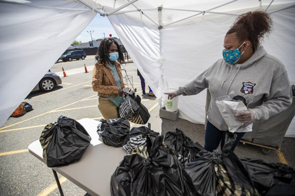 Jennifer Calderon, an advocate at Rosie's Place, assists a woman who's getting bags of groceries and supplies at the food pantry tent. (Jesse Costa/WBUR)