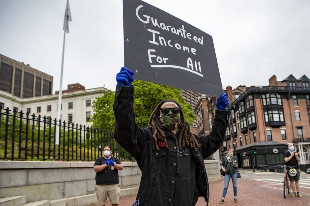 Armani White of the Black Boston COVID-19 coalition holds up a sign protesting in front of the State House for the black and Latino people who have died of COVID-19. (Jesse Costa/WBUR)