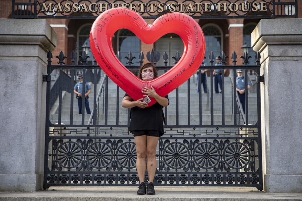 A protester stands at the gates of the Massachusetts State House. (Robin Lubbock/WBUR)