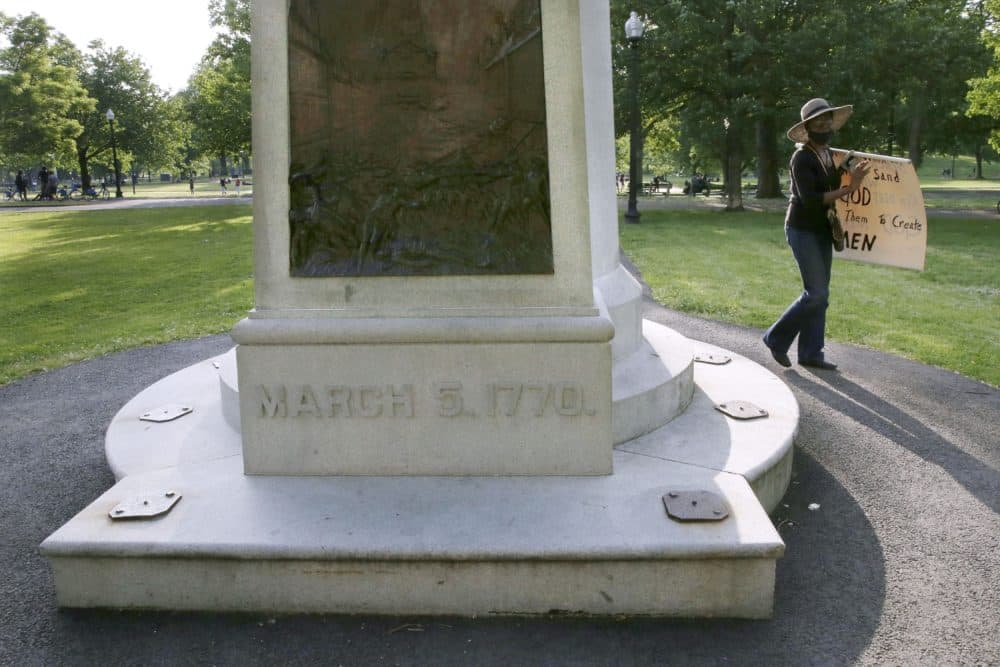 A woman walks past the Boston Massacre Monument on Boston Common on June 3, after a protest against police brutality following the death of George Floyd. The relief sculpture on the monument depicts Crispus Attucks, a black man and first person gunned down by British troops during the Boston Massacre on March 5, 1770. The attack helped touch off the American Revolution. (Charles Krupa/AP)