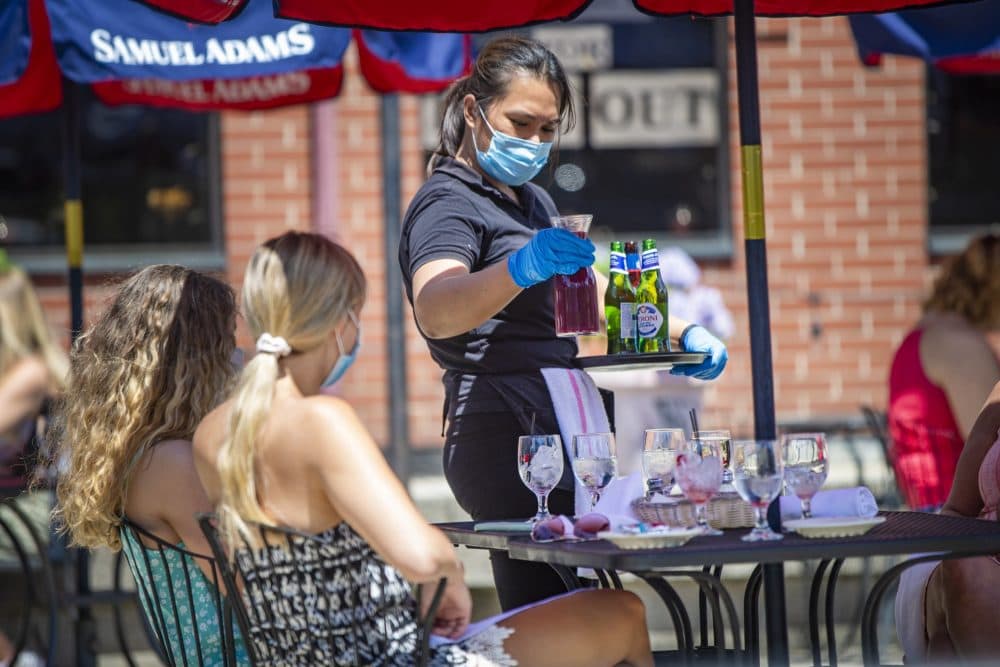 A server brought beverages to diners at Mother Anna’s in the North End in June. The reopening of restaurants and other businesses last month was not enough to lower the Massachusetts unemployment rate. (Jesse Costa/WBUR)