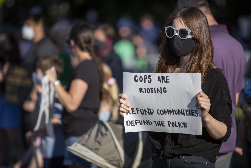 A protester in West Roxbury urges calls for defunding the police. (Robin Lubbock/WBUR)