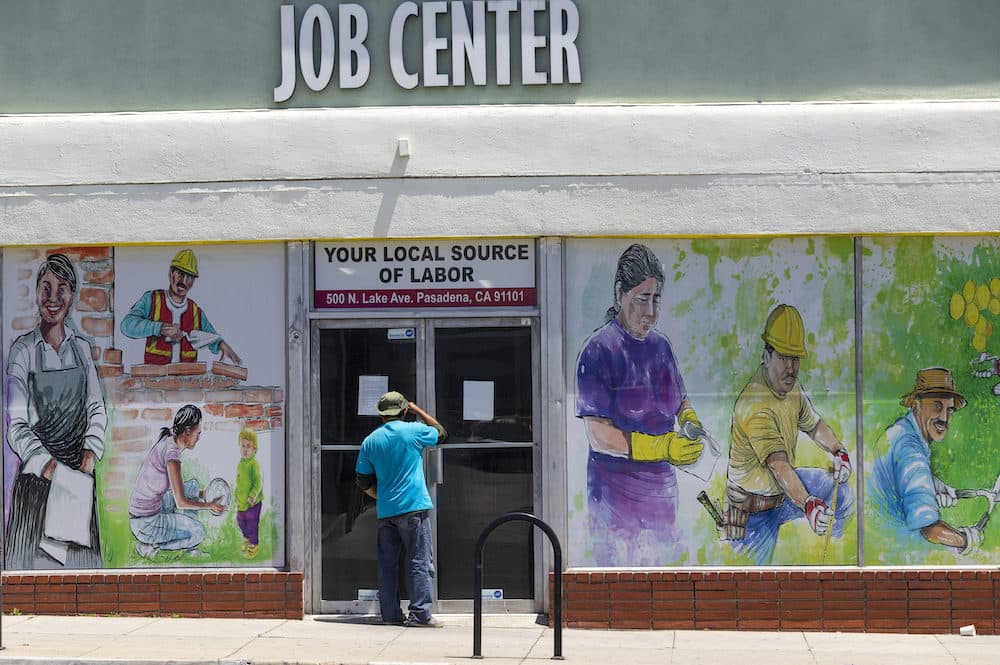 A worker looks inside the closed doors of the Pasadena Community Job Center in Pasadena, Calif., Thursday, May 7, 2020, during the coronavirus outbreak. (Damian Dovarganes/AP Photo)