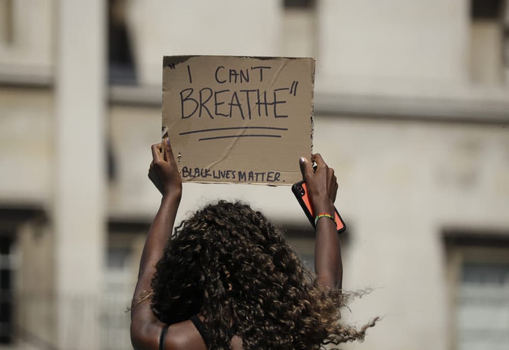 A woman holds up a banner as people gather in Trafalgar Square in central London on Sunday, May 31, 2020 to protest against the recent killing of George Floyd by police officers in Minneapolis that has led to protests across the US. (Matt Dunham/AP)