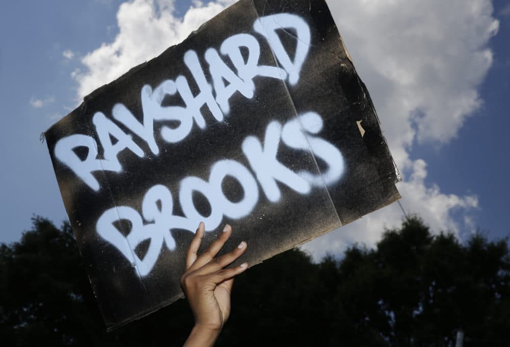 A protester holds up a sign on Saturday, June 13, 2020, near the Wendy's restaurant where Rayshard Brooks was shot and killed by police Friday evening following a struggle in the restaurant's drive-thru line in Atlanta. (Brynn Anderson/AP)