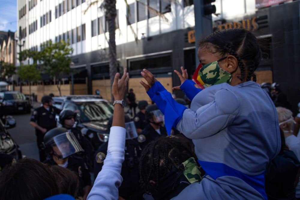 A child holds up his hands in front of a row of police officers in downtown Long Beach on May 31, 2020 during a protest against the death of George Floyd, an unarmed black man who died while being arrested and pinned to the ground by the knee of a Minneapolis police officer. (APU GOMES/AFP via Getty Images)