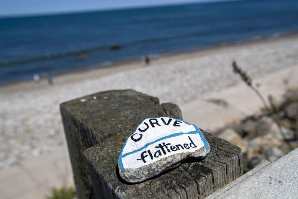 A brightly painted rock with a pandemic-related message was left on top of a guardrail at a virtually empty Brant Rock Beach in Marshfield. (Jesse Costa/WBUR)