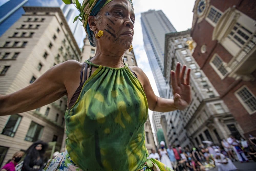 Isaura Oliveira dances around the marker at the site of the Boston Massacre, in front of the Old State House, during the Dismantle Now! BIPOC Solidarity Against White Supremacy demonstration. (Jesse Costa/WBUR)