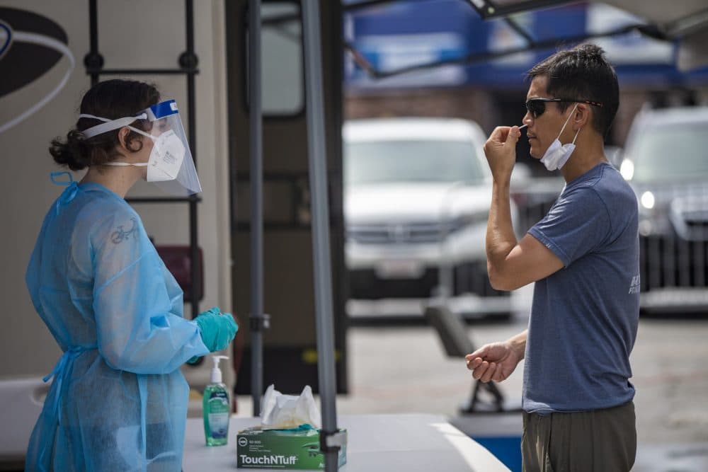 A Chelsea resident inserts a swab up his nose during free COVID-19 testing offered by the state in Chelsea Square. (Jesse Costa/WBUR)